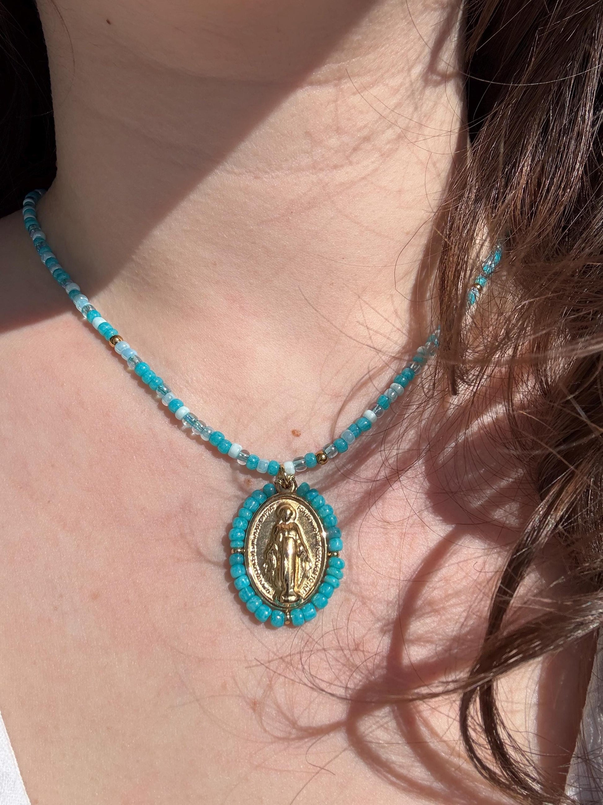 Femme portant un collier Médaille Miraculeuse perlée bleu turquoise