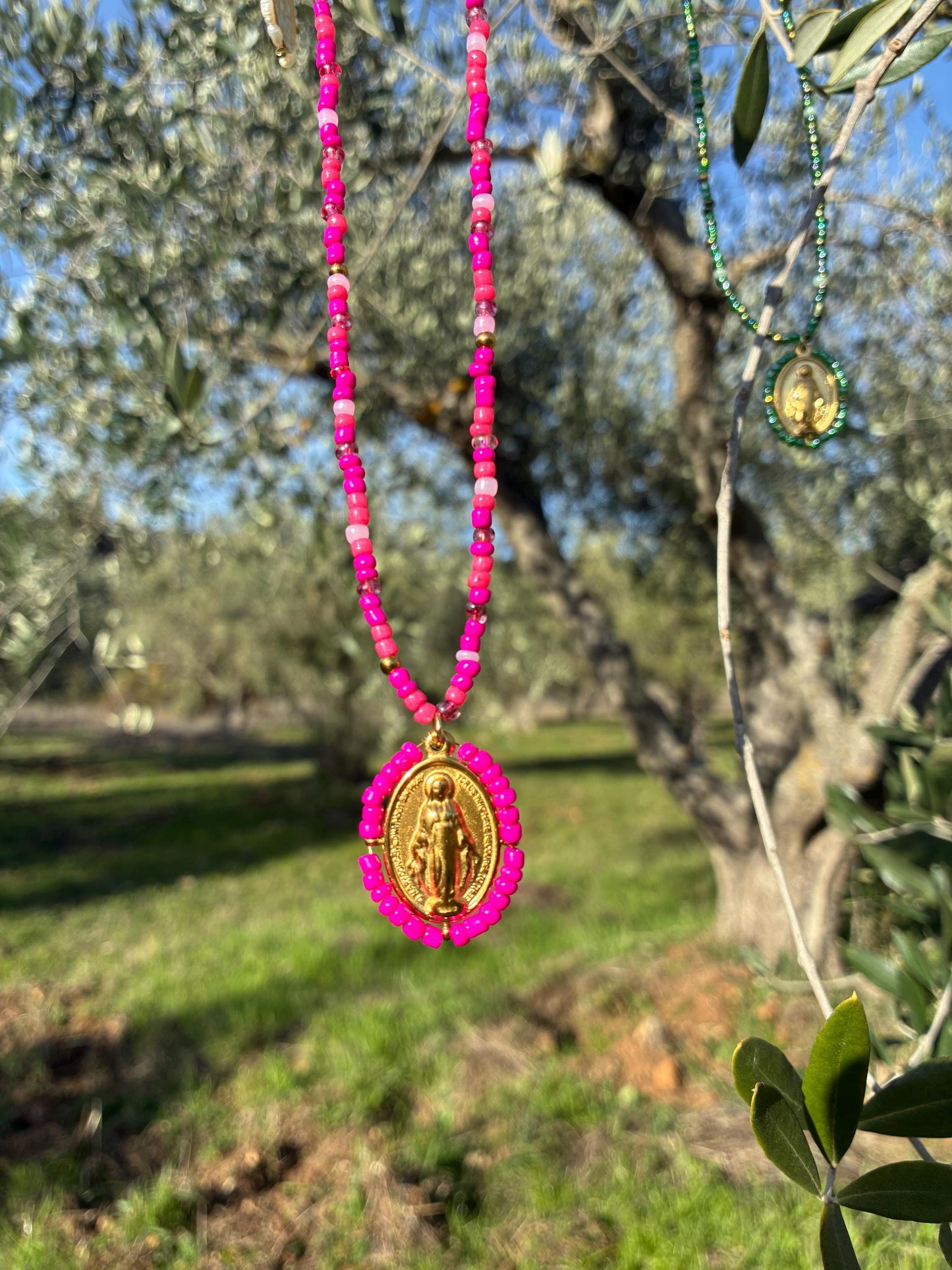 Collier Médaille Miraculeuse perlée rose fuchsia suspendu en extérieur