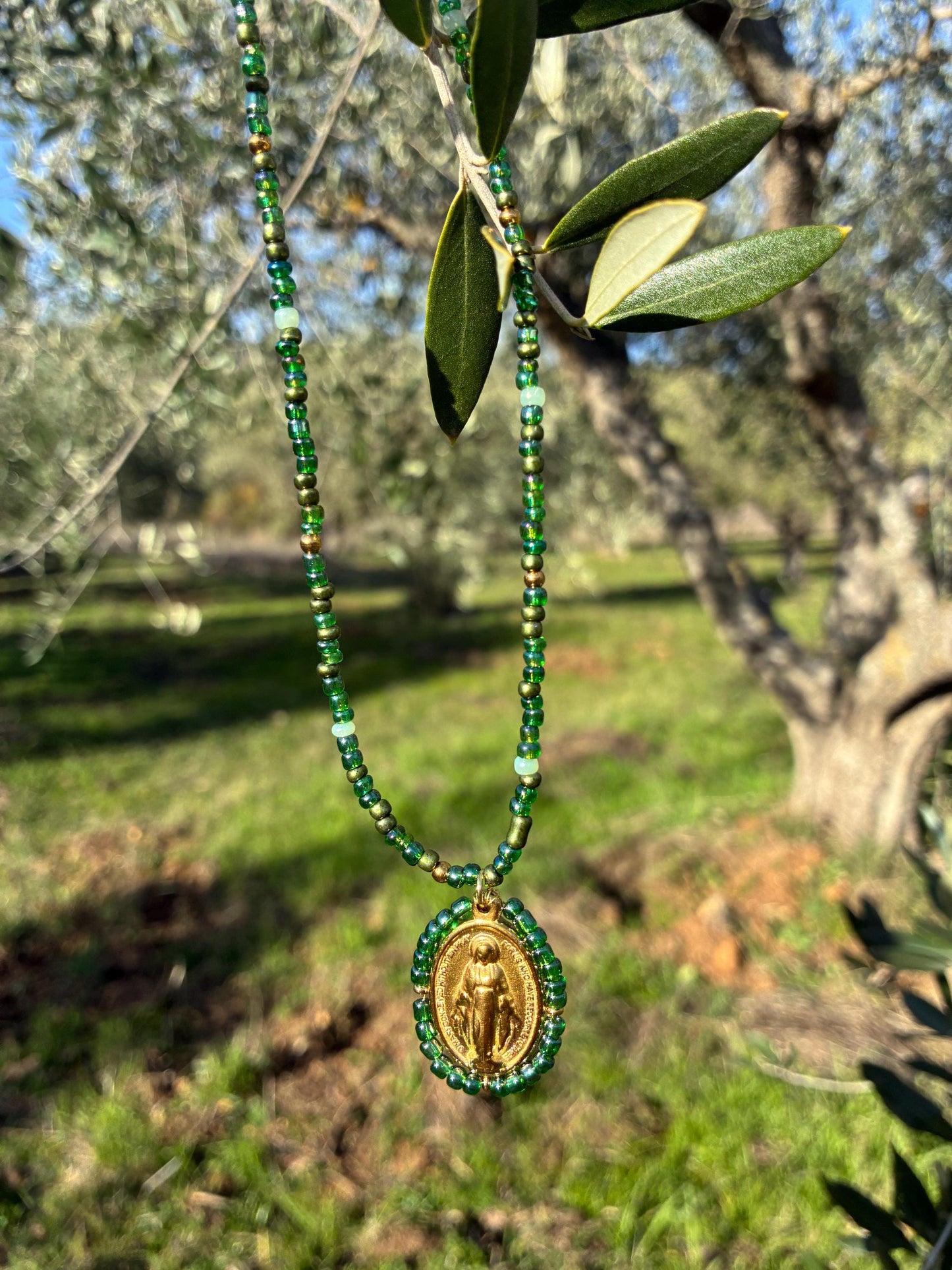 Collier Médaille Miraculeuse perlée verte suspendu à une branche d'olivier