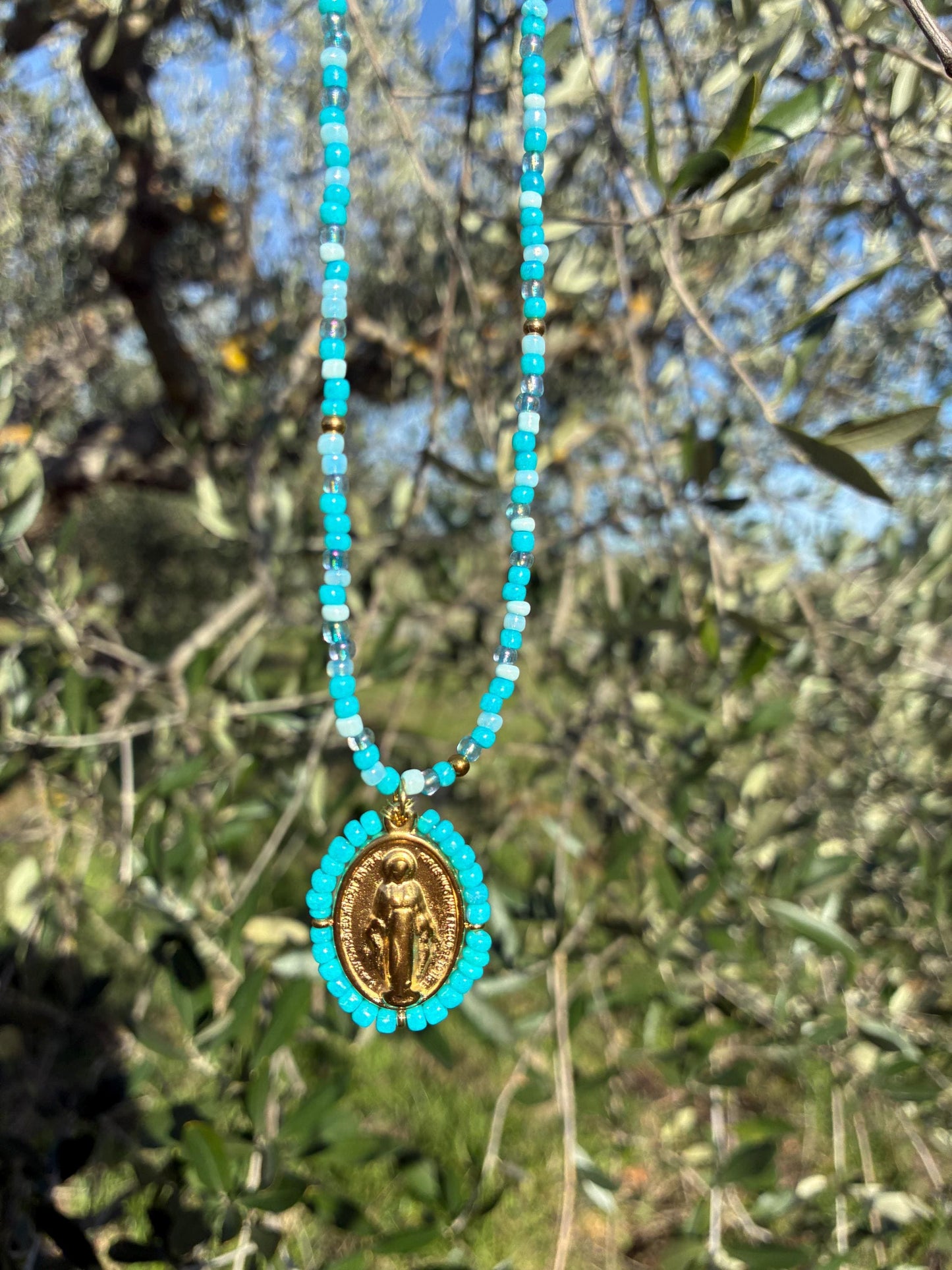Collier Médaille Miraculeuse perlée bleu turquoise suspendu à un olivier