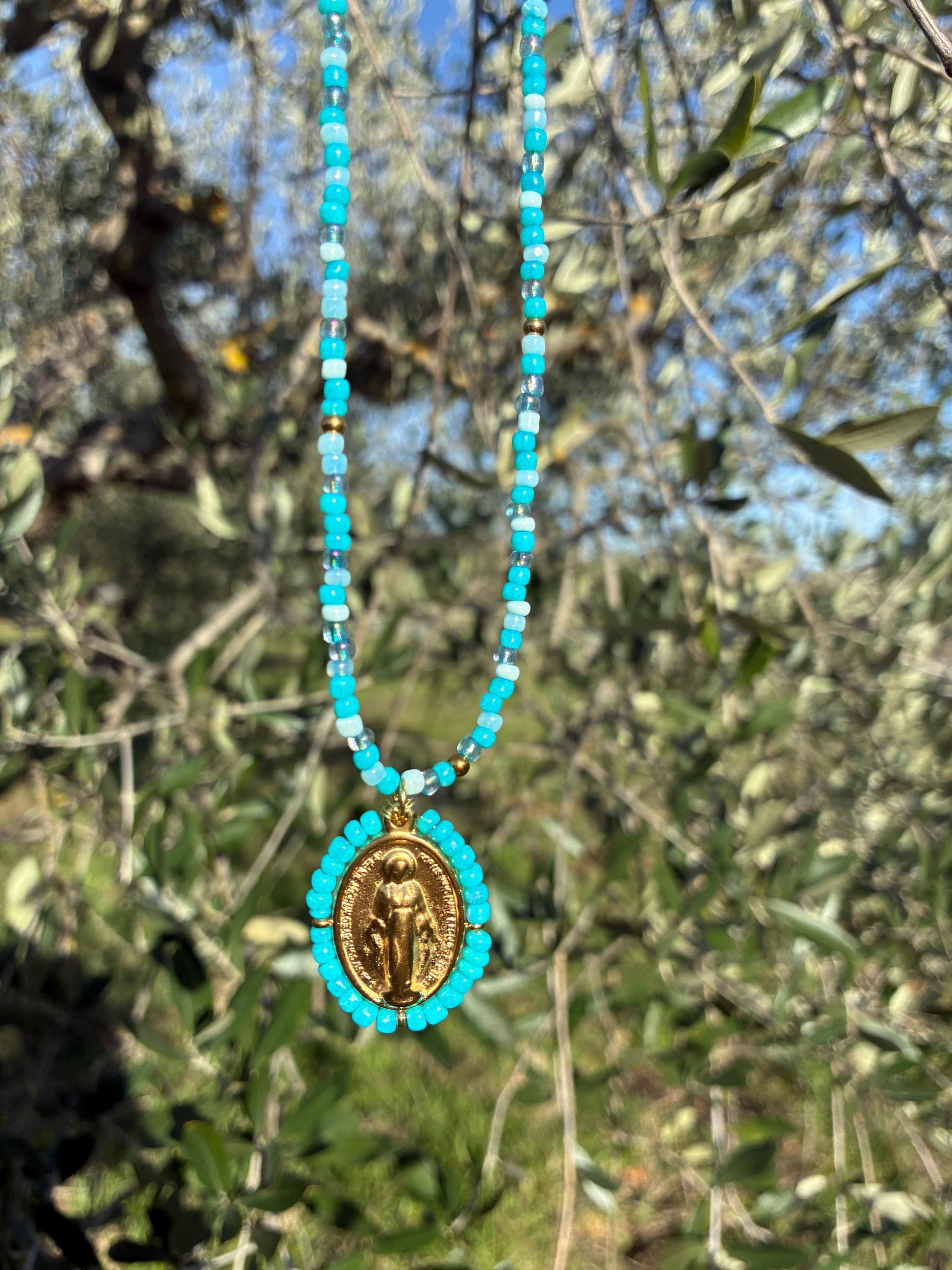 Collier Médaille Miraculeuse perlée bleu turquoise suspendu à un olivier